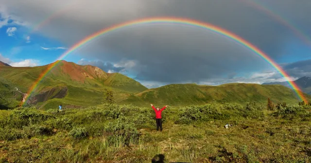 アラスカの山並みにかかる明るい虹と、その外側の左右に見える薄い虹