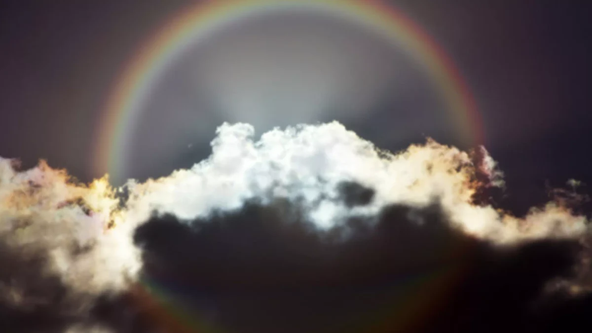雲を背景に、下側へも弧が続く円形の虹。輪の一部は雲や画面の端に隠れている